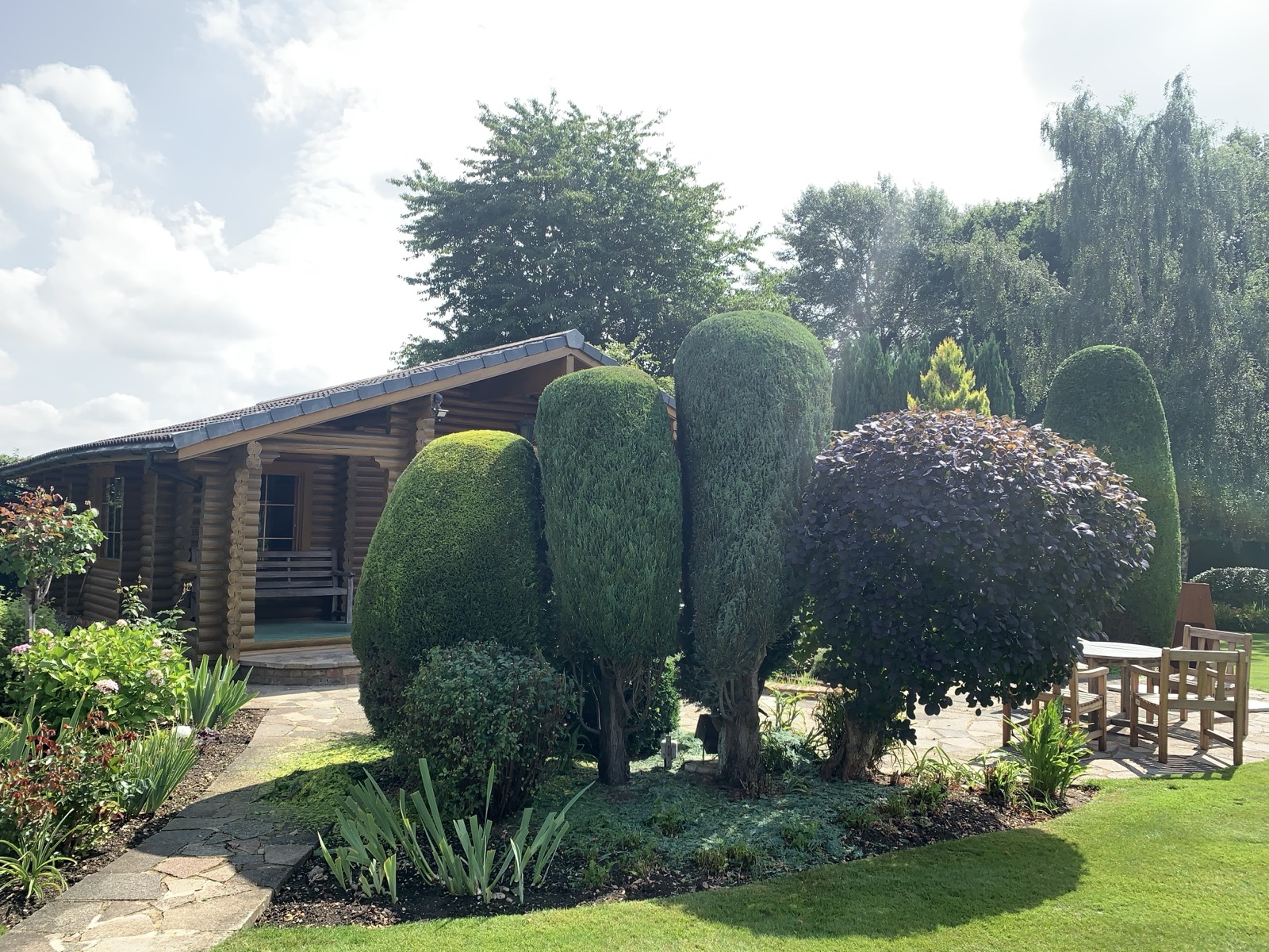 Cloud-pruned and shaped topiary maintained around a garden lodge.